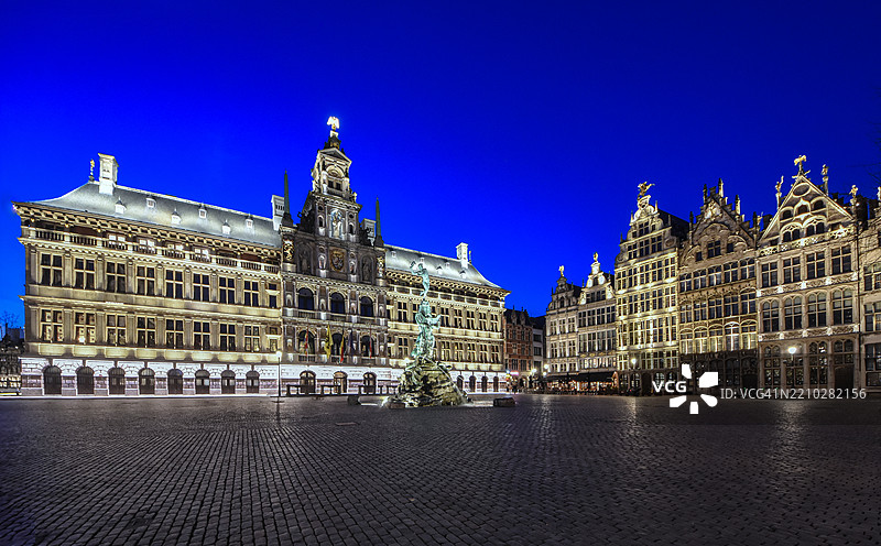 中世纪安特卫普的“大广场”(“Grote Markt”)在黄昏时分灯光璀璨,浪漫的天空下,显眼的市政厅建筑和“布拉博喷泉”(“Brabofontein”)喷泉位于其间,位于比利时弗拉芒大区的安特卫普。图片素材