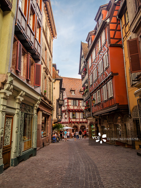 科尔马中世纪老城的鹅卵石步行街宽角度视图，两旁是传统的多彩半木结构建筑，里面有商店、餐馆和咖啡馆，位于阿尔萨斯的上莱茵省，东法兰西。图片素材