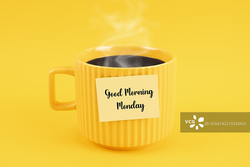 黄色背景上，黄色杯子里的黑咖啡，杯子上写着“早安，星期一”。图片素材