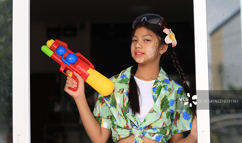 可爱的亚洲女孩穿着夏季宋干节服装，手持水枪庆祝宋干节，泰国新年。图片素材