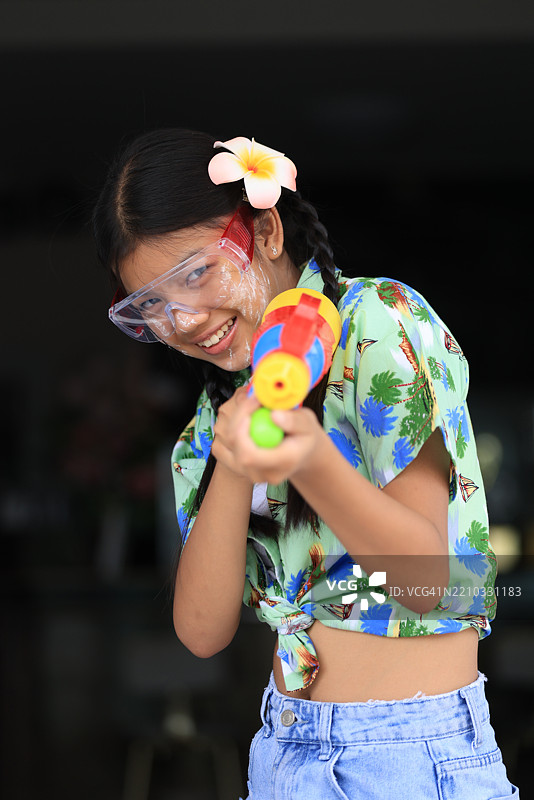 可爱的亚洲女孩穿着夏季宋干节服装，手持水枪庆祝宋干节，泰国新年。图片素材