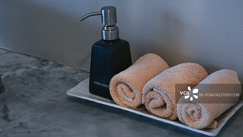 三卷手巾放在一瓶洗手液旁，提供实用且卫生的手部清洁设置。图片素材