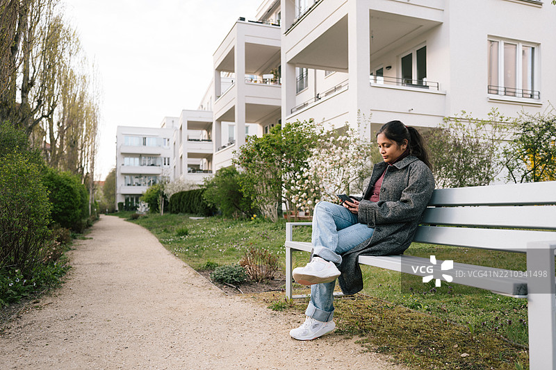 年轻女性坐在长椅上看手机图片素材