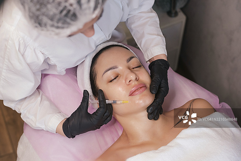 女性在美容院接受面部美容注射图片素材