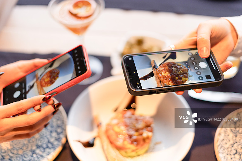 顾客在餐厅用智能手机拍摄食物图片素材