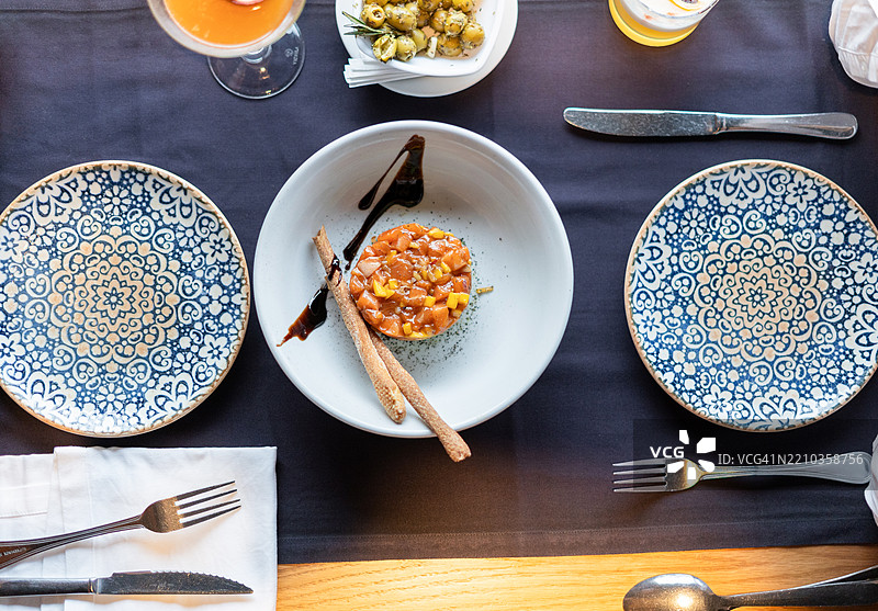 优雅的餐桌布置上摆放着三文鱼塔塔、脆饼棒和饮品图片素材