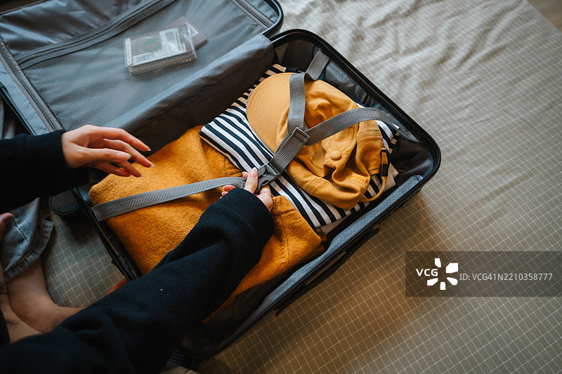 女人在家中为假期旅行打包行李箱。图片素材