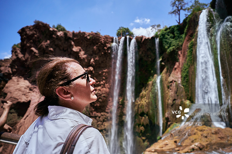 成熟的白人女性游客在摩洛哥欣赏瀑布。图片素材