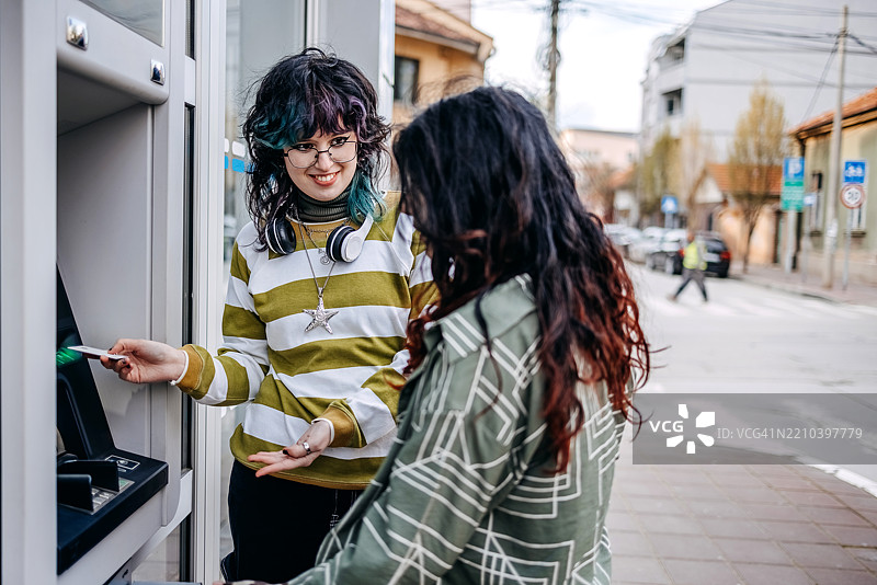 少女在户外的ATM机前取款，正在使用信用卡。图片素材