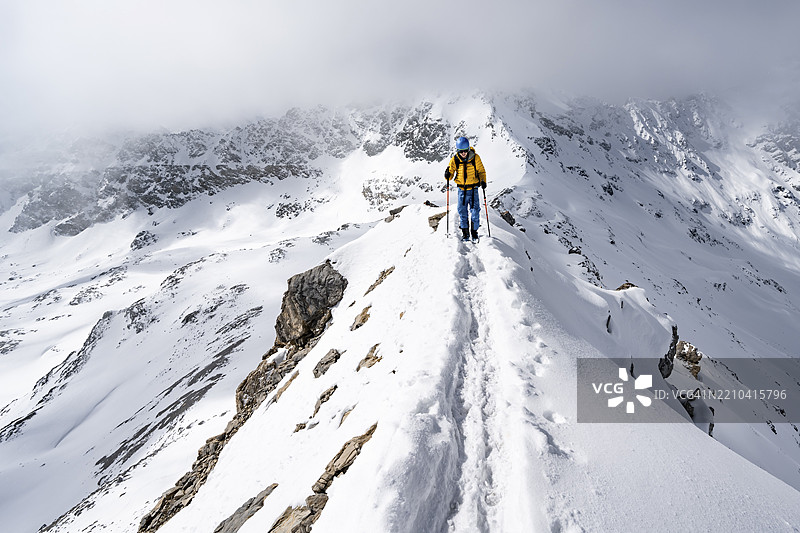 登山者攀爬皮茨·拉维纳尔的狭窄山脊，冬季山景尽收眼底，格劳宾登高路线，阿尔布拉阿尔卑斯山，瑞士莱蒂安阿尔卑斯山，格劳宾登，瑞士东部，欧洲图片素材