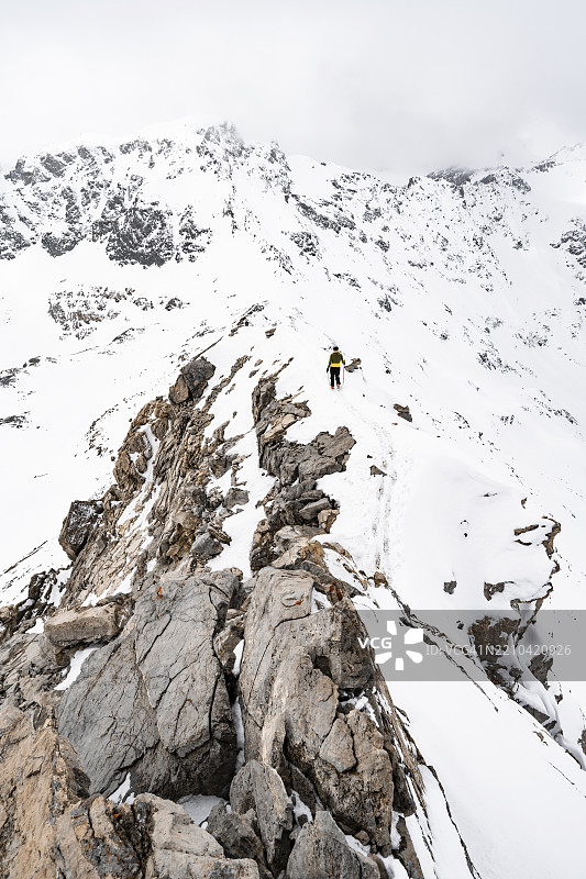 登山者在皮茨·拉维纳尔的狭窄山脊上下降，冬季山景中的山脉全景，格劳宾登高路线，阿尔布拉阿尔卑斯山，瑞士莱蒂安阿尔卑斯山，格劳宾登，瑞士东部，欧洲图片素材