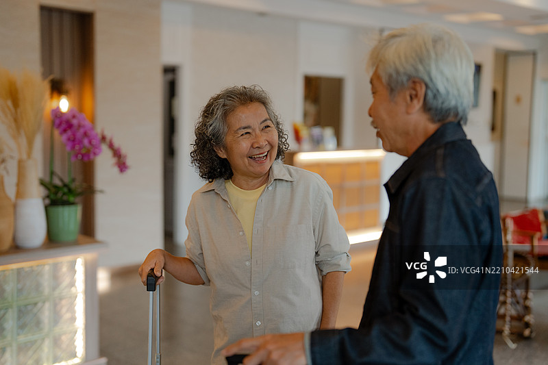 一对老年夫妇坐在现代酒店大堂里，正在交谈。图片素材