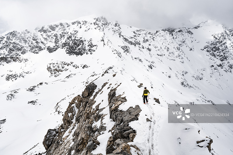 登山者在皮兹·拉维纳尔的狭窄山脊上下降,冬季山地风景中的山脉全景,格劳宾登高路线,阿尔布拉阿尔卑斯山,瑞士莱蒂安阿尔卑斯山,格劳宾登,瑞士东部,欧洲图片素材