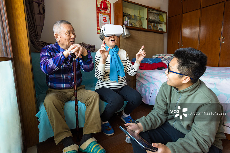 祖父母与孙子孙女一起戴着虚拟现实头盔在家中玩游戏图片素材