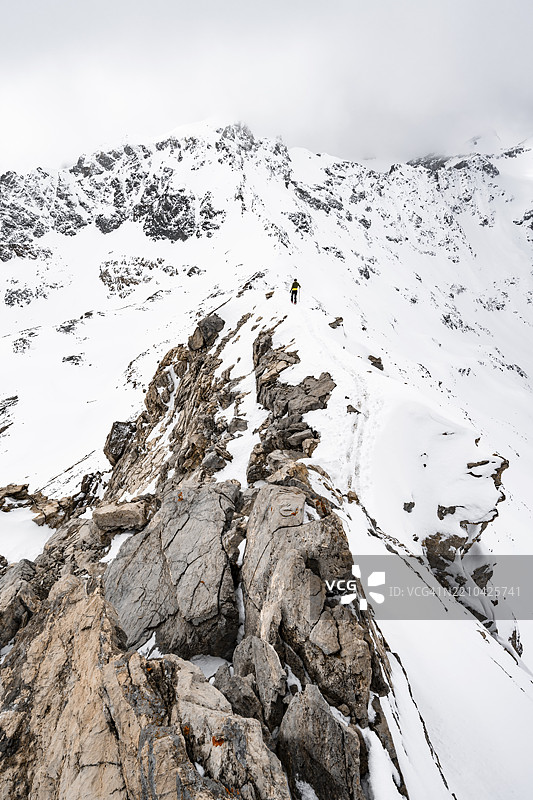 登山者在皮茨·拉维纳尔的狭窄山脊上下降，冬季山地风景中的山脉全景，格劳宾登高路线，阿尔布拉阿尔卑斯山，瑞士莱蒂安阿尔卑斯山，格劳宾登，瑞士东部，欧洲图片素材