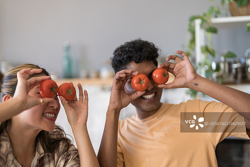 快乐的情侣在厨房里玩番茄图片素材