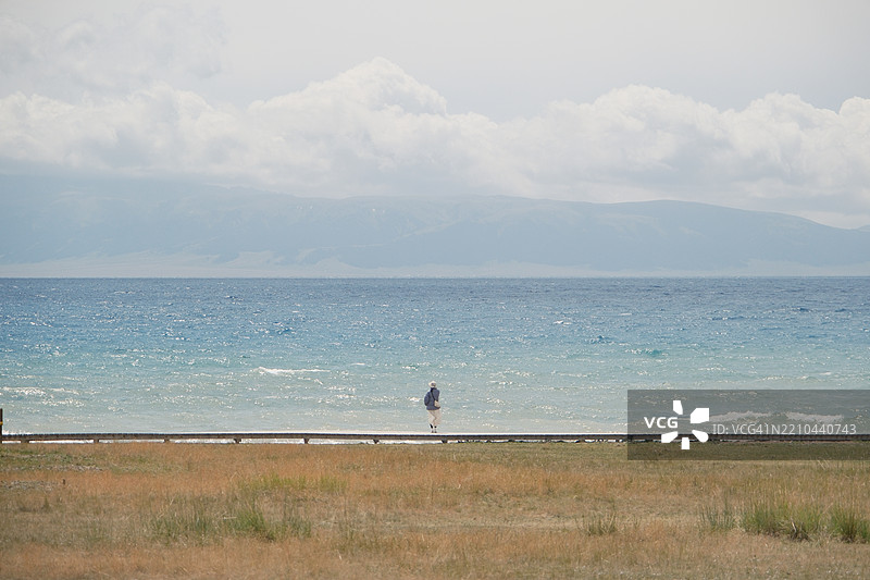 背影的女性站在海滩上，背景是天空图片素材