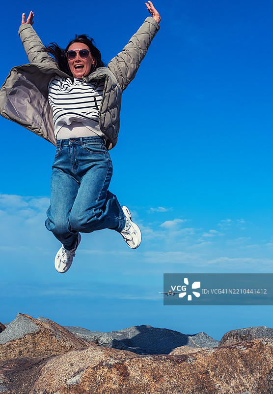 低角度视图的女性在蓝天中跳跃图片素材