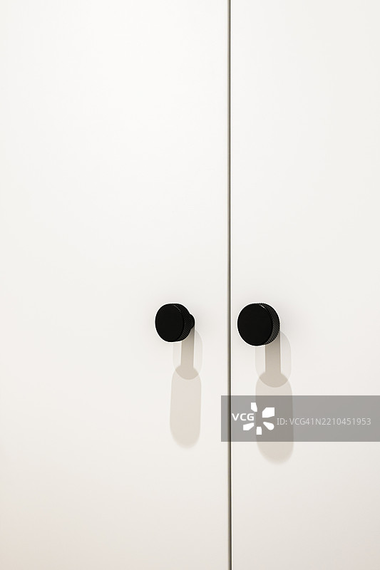 现代黑色纹理衣柜把手特写，背景为白色表面图片素材