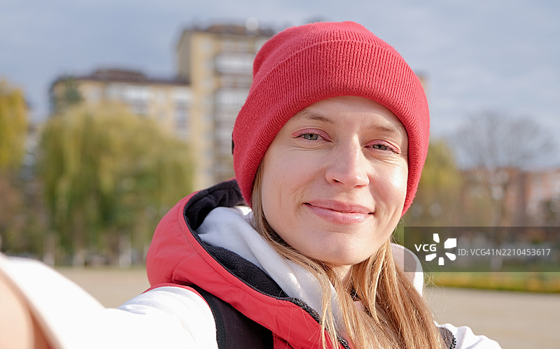 游客女性在公园里坐着，手持地图探索新城市，同时使用手机。图片素材