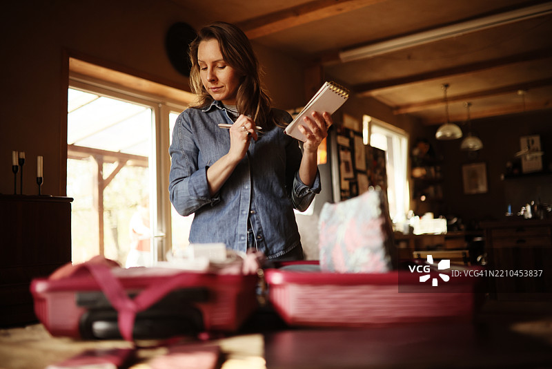 女人在打包行李，查看清单上的物品图片素材