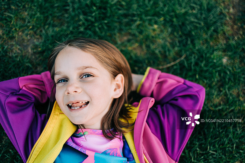 无忧无虑的小女孩在生机勃勃的绿草上放松，享受户外宁静的时刻图片素材