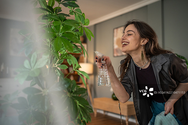 年轻女性在公寓里浇水给植物图片素材