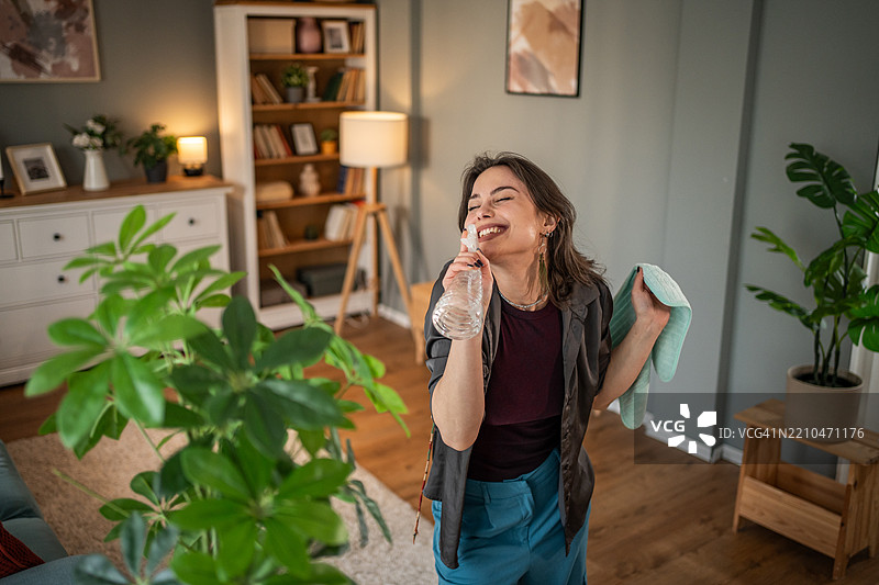 年轻女性一边用喷雾瓶和布清洁公寓，一边唱歌图片素材
