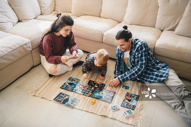 年轻家庭向他们的男孩展示一款桌游。图片素材