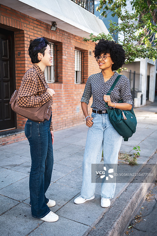 两个朋友在阳光明媚的街道上交谈图片素材