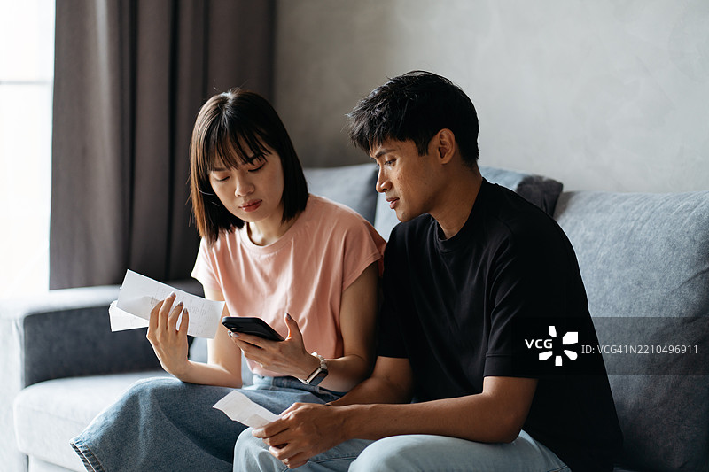 担忧的亚洲夫妇在查看他们的财务状况图片素材