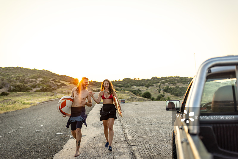 一对情侣带着冲浪板在海滩上冲浪图片素材