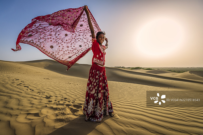 快乐的印度女孩在沙丘上跳舞，沙漠村庄，印度图片素材