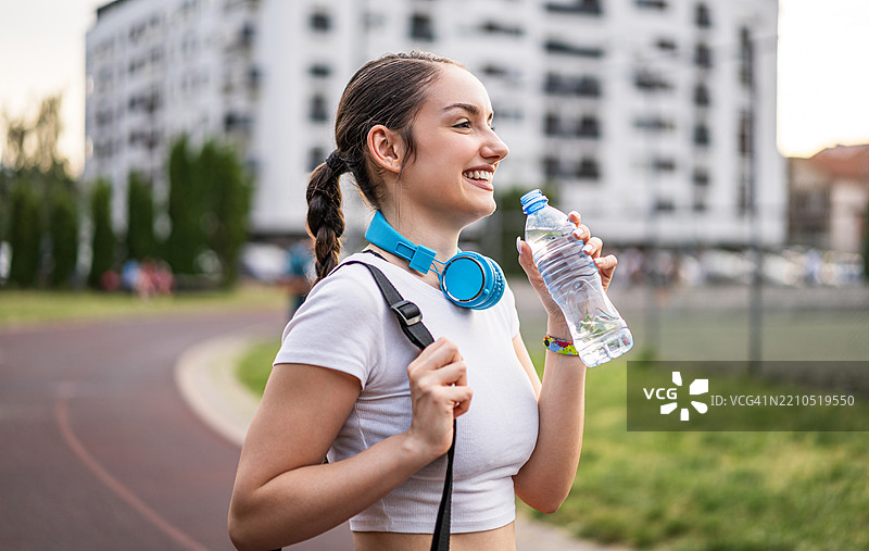 年轻的运动女性在户外训练后喝水图片素材