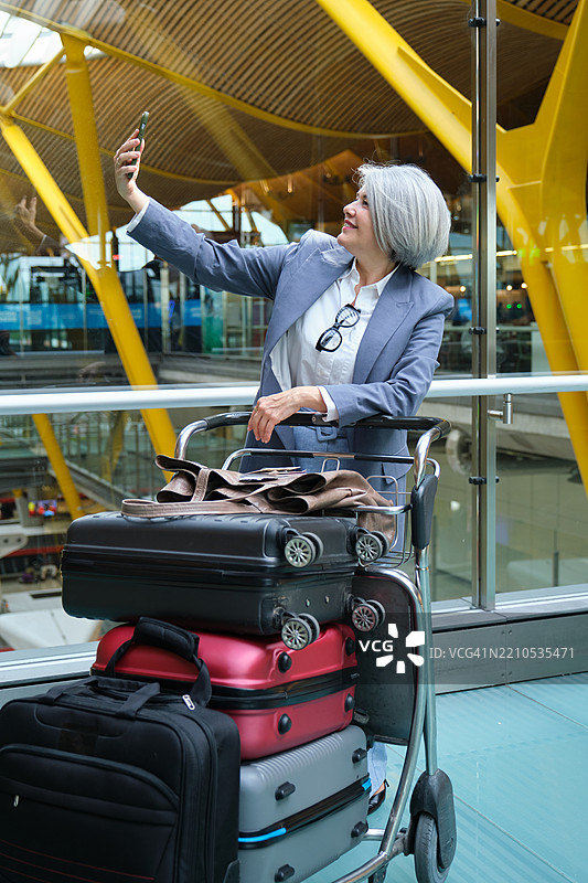 高级女商人在机场用行李推车自拍图片素材