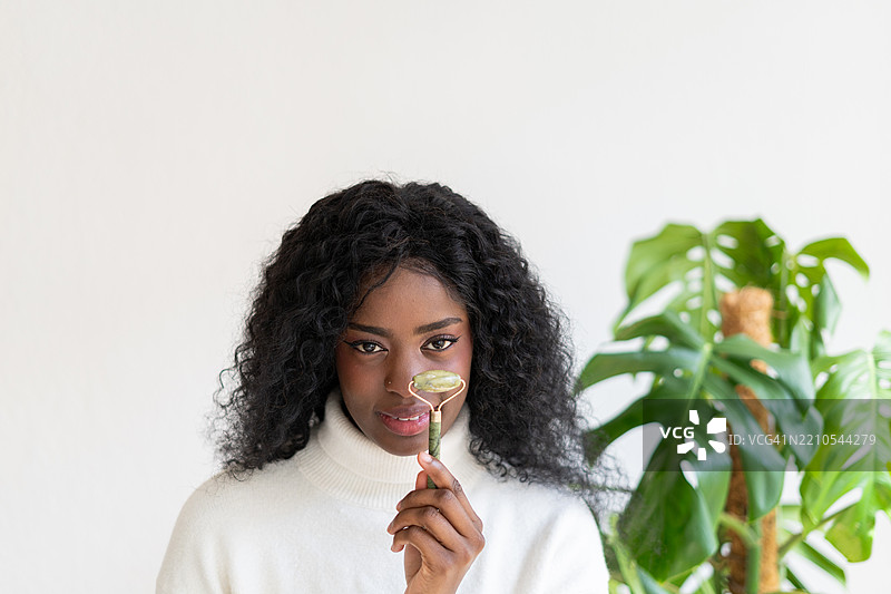 年轻女性在家使用玉石滚轮进行面部按摩图片素材