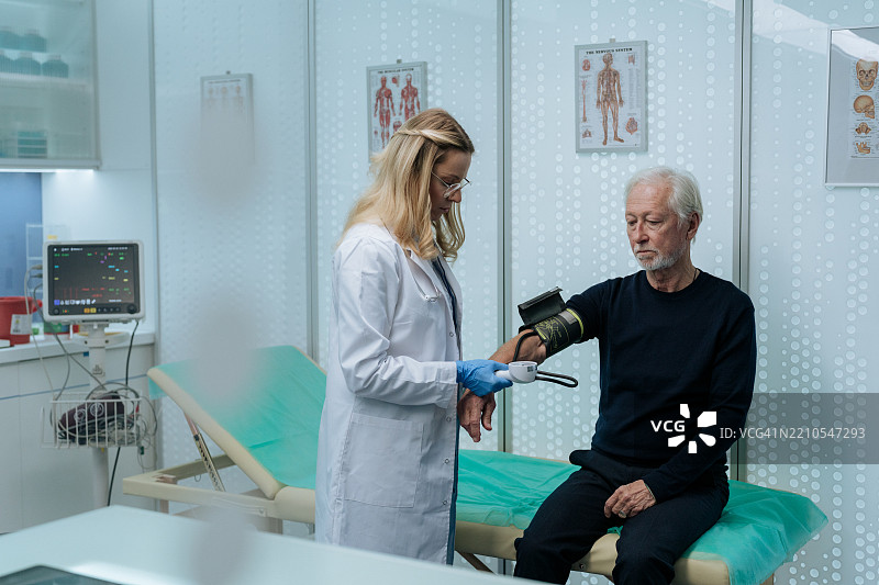 女医生在诊所为老年男性患者测量血压，正在给他戴上血压袖带。图片素材