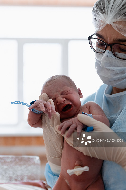医生在医院中抱着新生儿，进行医疗护理和观察图片素材