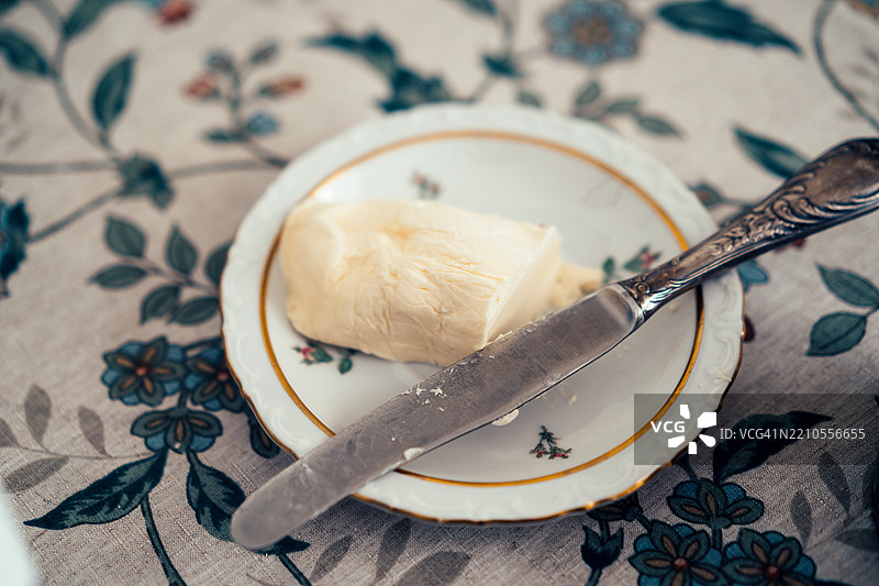 自制黄油放在小碟子上，旁边有一把涂抹用的餐刀图片素材
