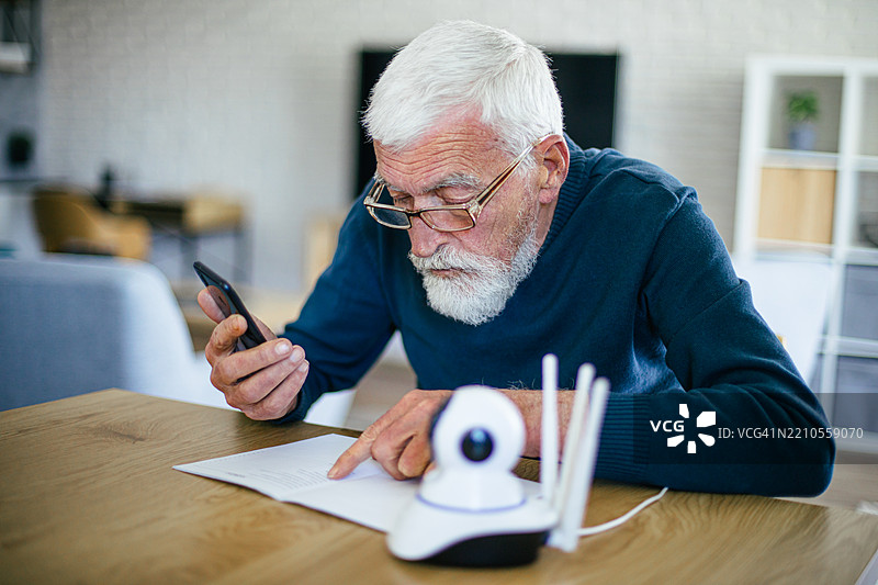 老年男子尝试安装他的IP监控摄像头，正在阅读说明书图片素材