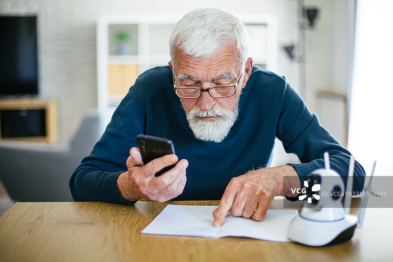 老年男子尝试安装他的IP监控摄像头，正在阅读说明书图片素材