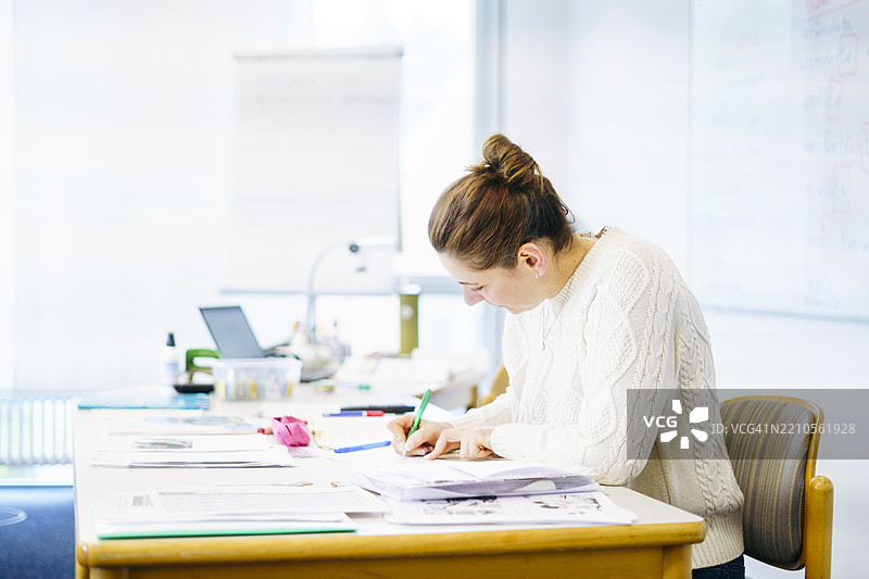 教师在教室的桌子上写笔记图片素材