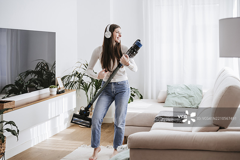 在家里戴着耳机的女人与吸尘器跳舞图片素材