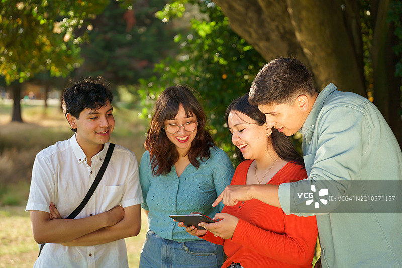 一群学生在公园里共享一台平板电脑图片素材