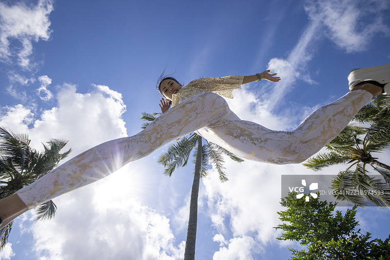 穿着现代健身服的女性在蓝天下户外锻炼图片素材