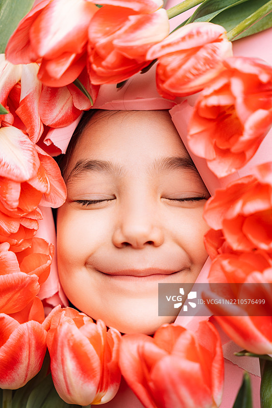 快乐孩子的特写肖像，周围环绕着郁金香图片素材
