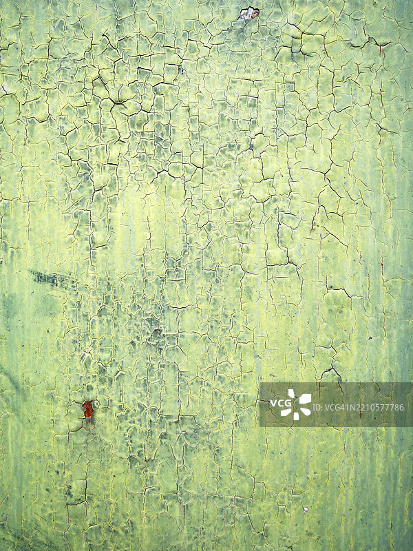 金属板上带有铜绿和裂纹的黄绿色油漆。有锈迹。纹理粗糙。阳光。自然色彩。法国巴黎。图片素材