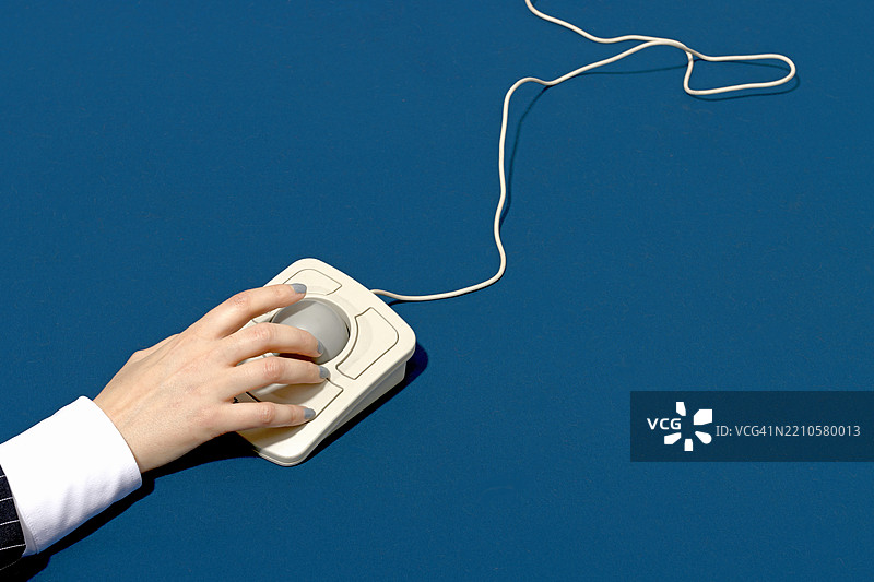 手在蓝色背景上使用复古轨迹球鼠标图片素材