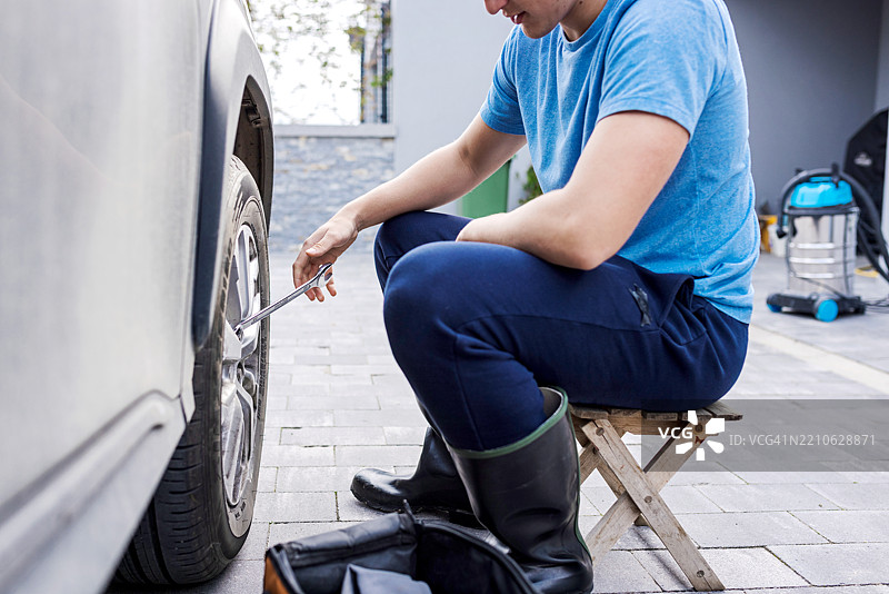 男子在车道上用扳手修理车辆轮胎图片素材