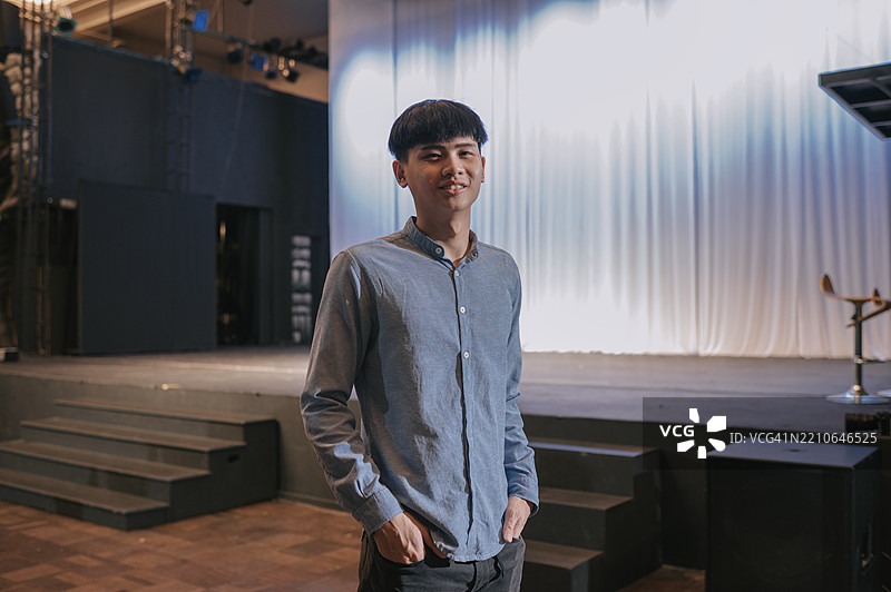 自信的亚洲年轻男子站在剧院舞台上图片素材